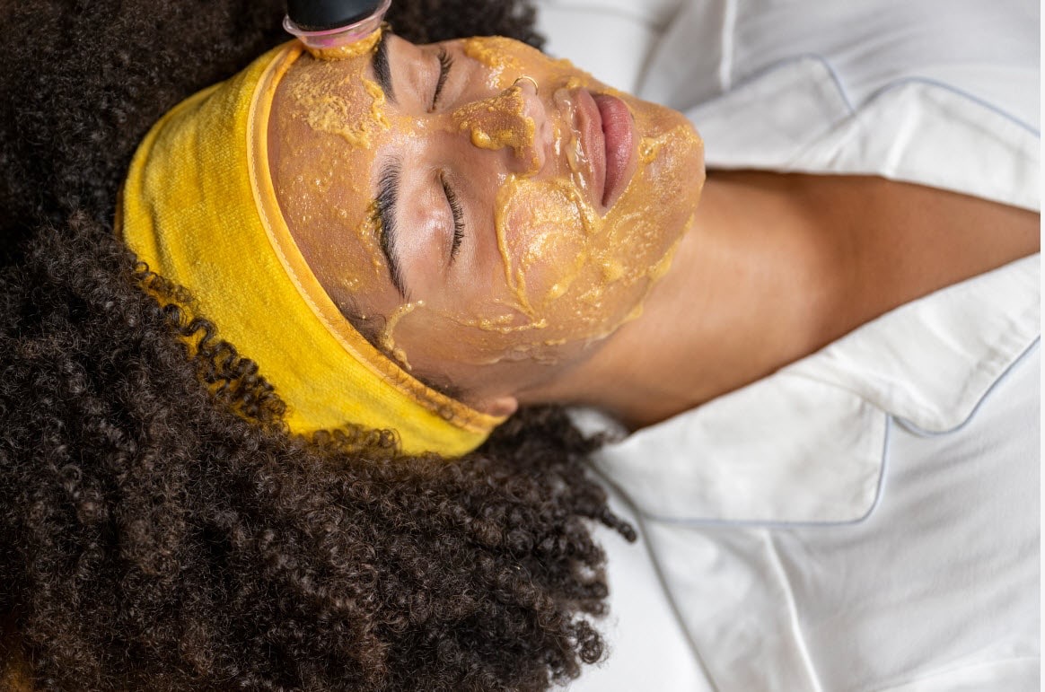 A photo of a woman getting a facial at a spa.