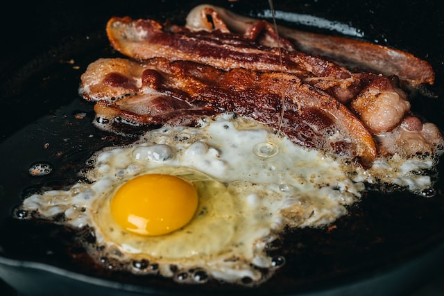 A keto diet is more strict than low-carb and has an emphasis on high fat foods. Here we see greasy bacon and eggs sizzling on a skillet.