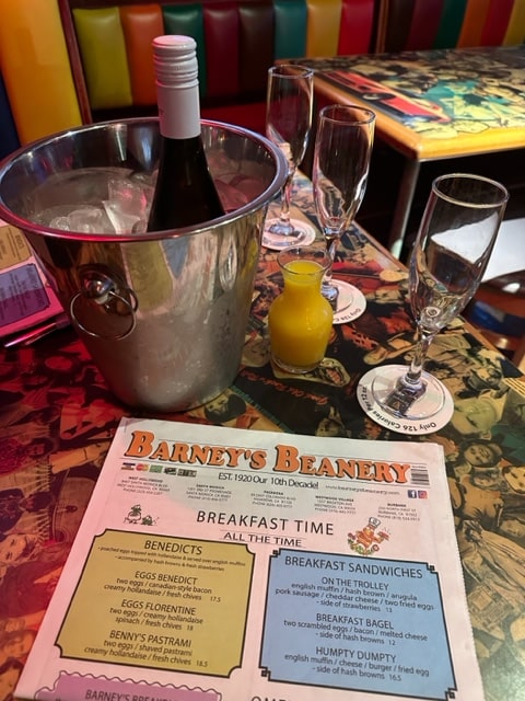 A photo of Barney's Beanery, the menu, champagne flutes and a bottle of champagne.