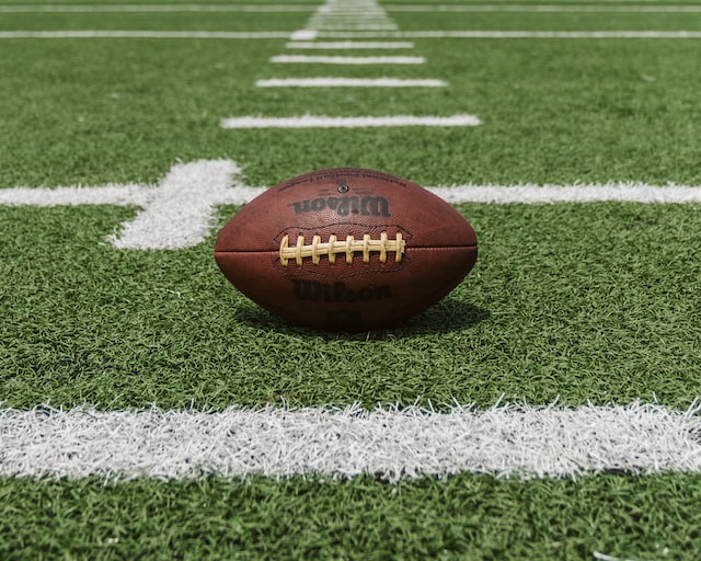 A photo of a football laying on a football field.