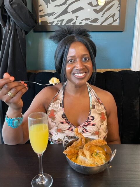 A photo of Ariel eating Catfish & Grits and a Mimosal.