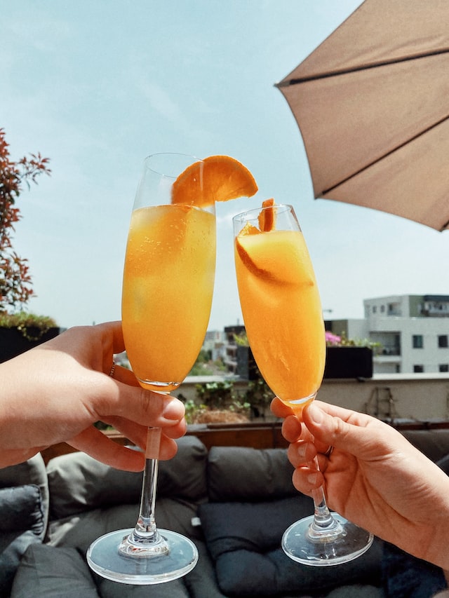 A photo of two people holding Mimosas.