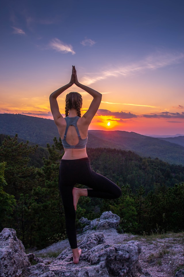 An image of a woman doing a yoga pose on top of a mountain in Ojai.