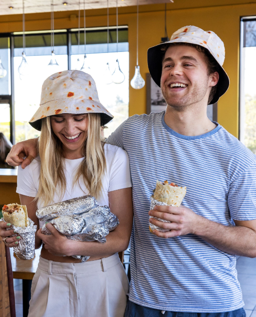 An image of a man and women holding burritos