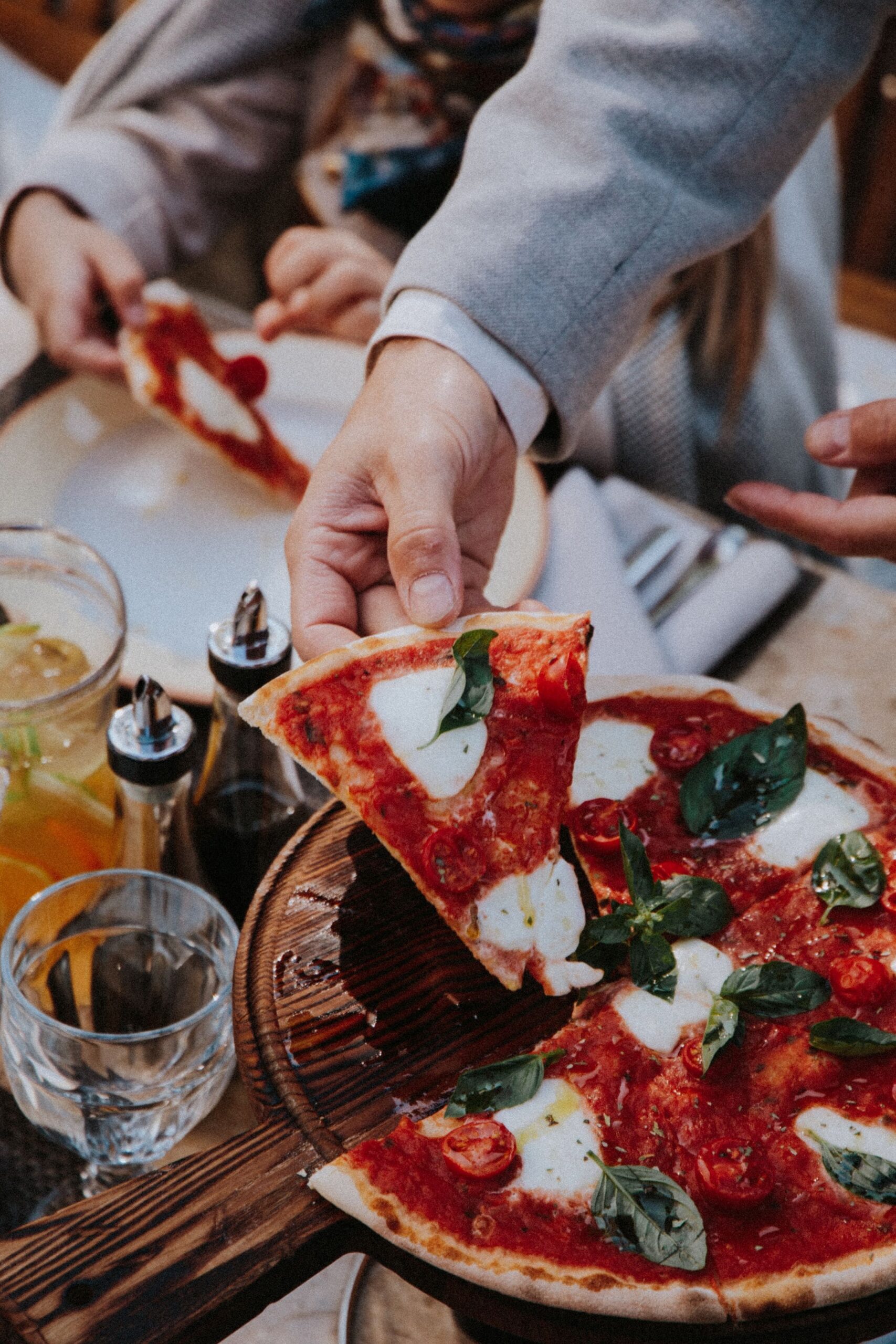 An image of someone grabbing a slice of Neapolitan pizza.