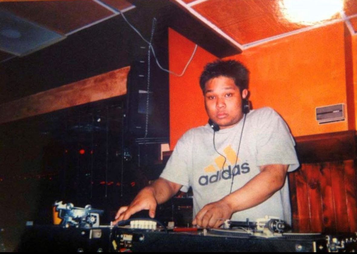An image of a young DJ Bonics spinning on his turntables. 