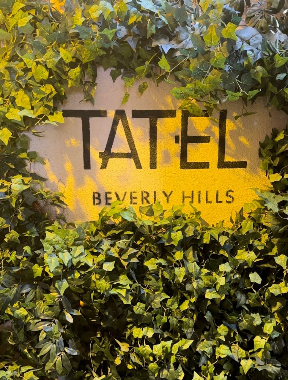 An image of the TATEL sign covered in greenery.