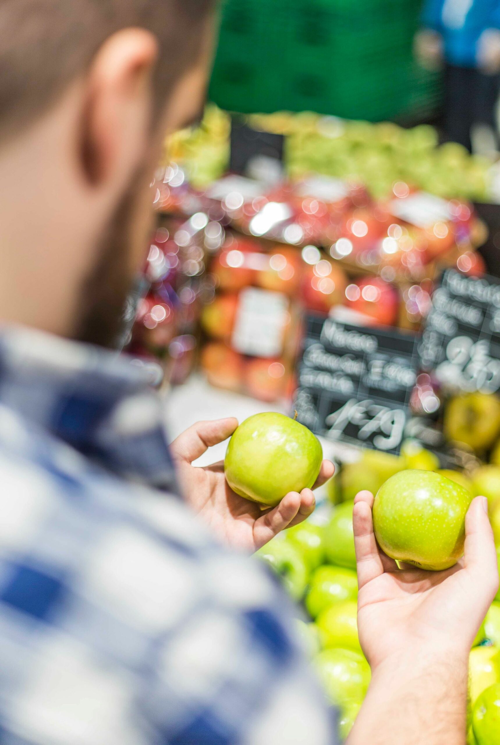 An image of a man holding apples in a grocery store.