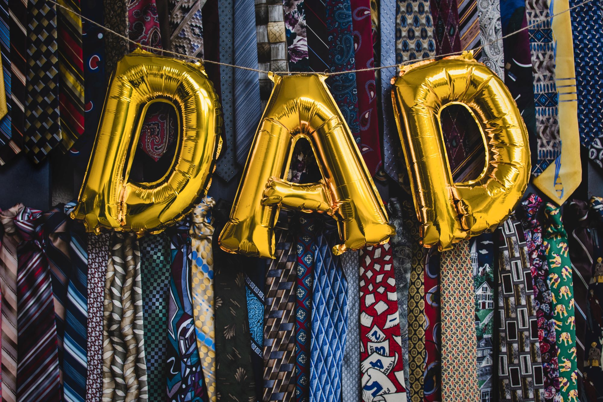 An image of a bundle of ties with the word 'Dad' spelled in balloons. 
