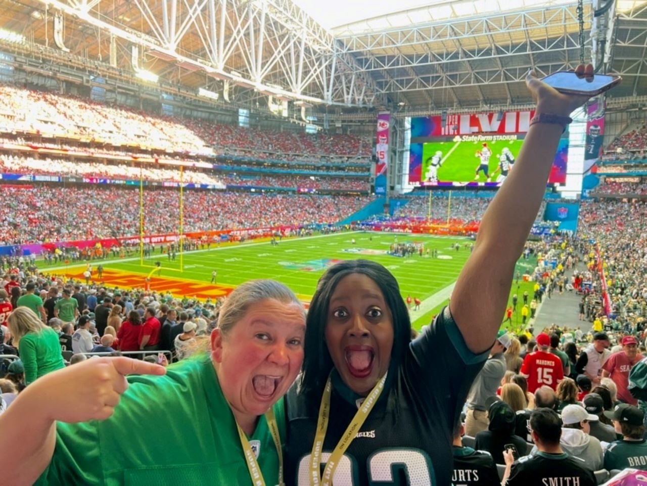An image of two women at the Super Bowl with the field behind them.