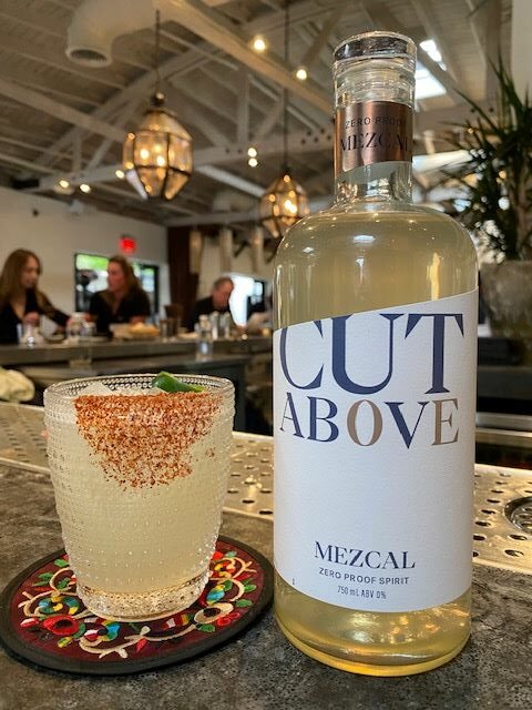 An image of Cut Above's Zero Proof Mezcal, and a cocktail. 