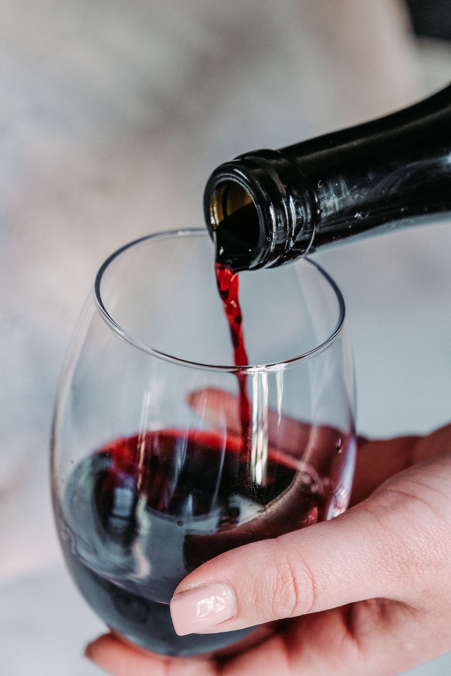 An image of a person holding a glass of red wine.