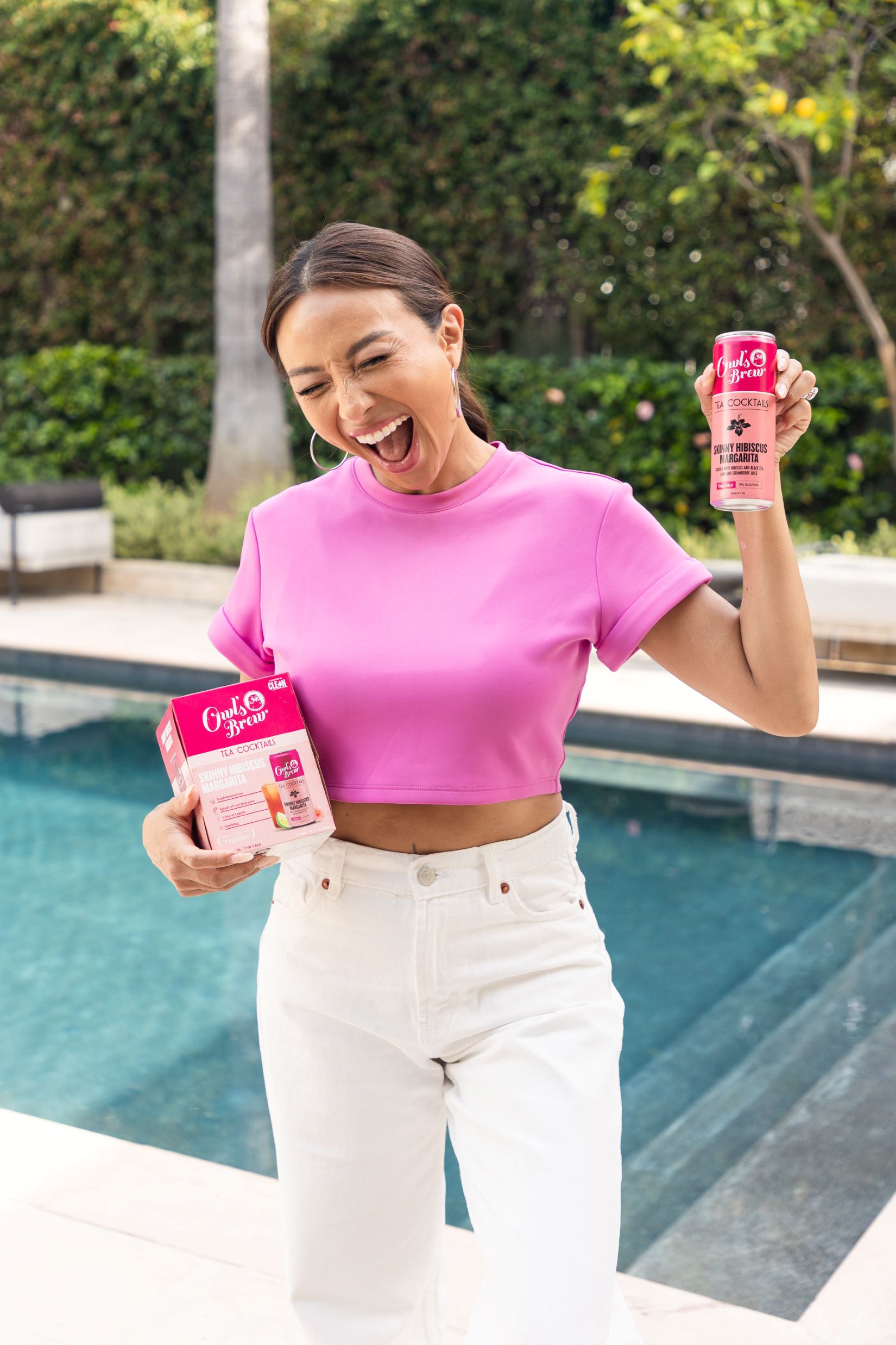 An image of Jeannie Mai cheering with a can of Owl's Brew Skinny Margarita