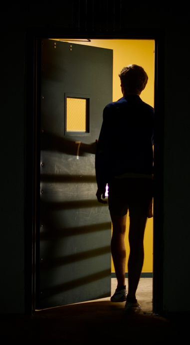 An image of a scary doorway. A man walks through a door that looks scare on the other side.
