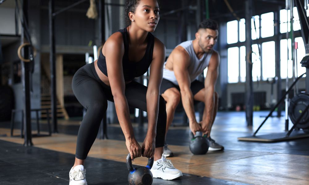 An image of a woman and man using kettle bells. 
