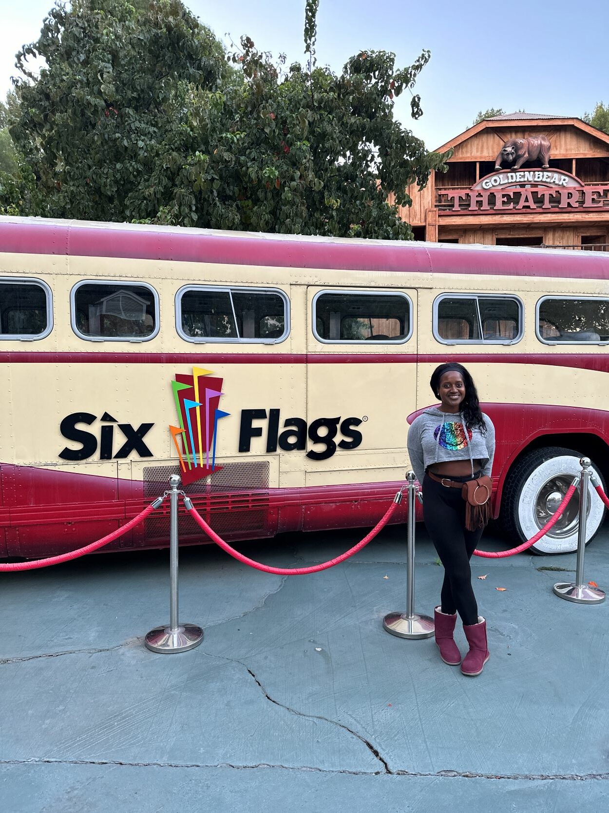 An image of a woman standing in front of a bus with the Six Flags logo on it.