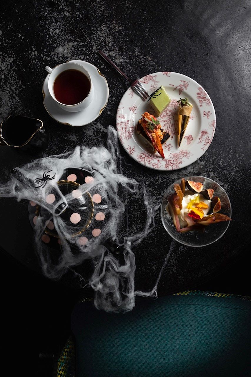 An image of the spooky tea at Lilly Rose. Pictured is a tea pot, fake spider webs, tea sandwiches, and a cup of tea.