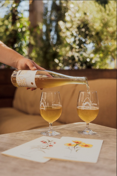 An image of someone pouring a bottle of Bloom wine and two wine glasses. 