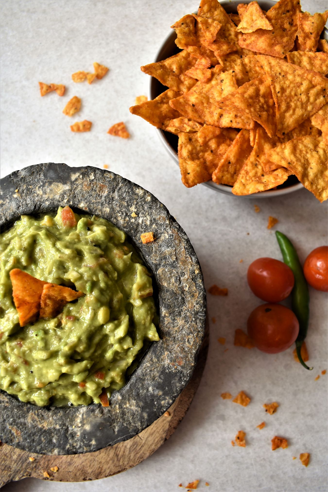 An image of a bowl of guacamole and chips on the side. 