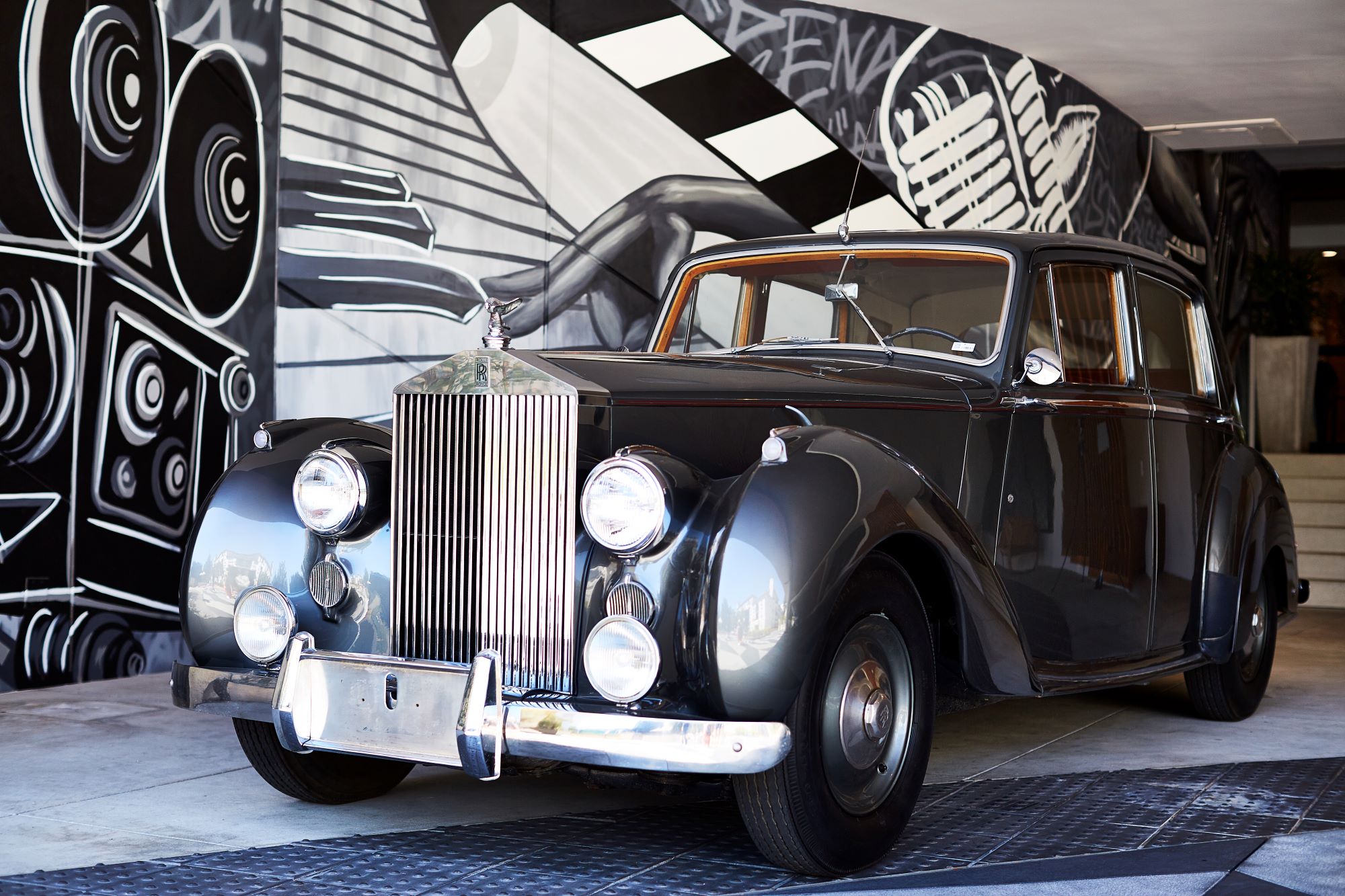 An image of the vintage Bentley and mural outside Hotel Dena.