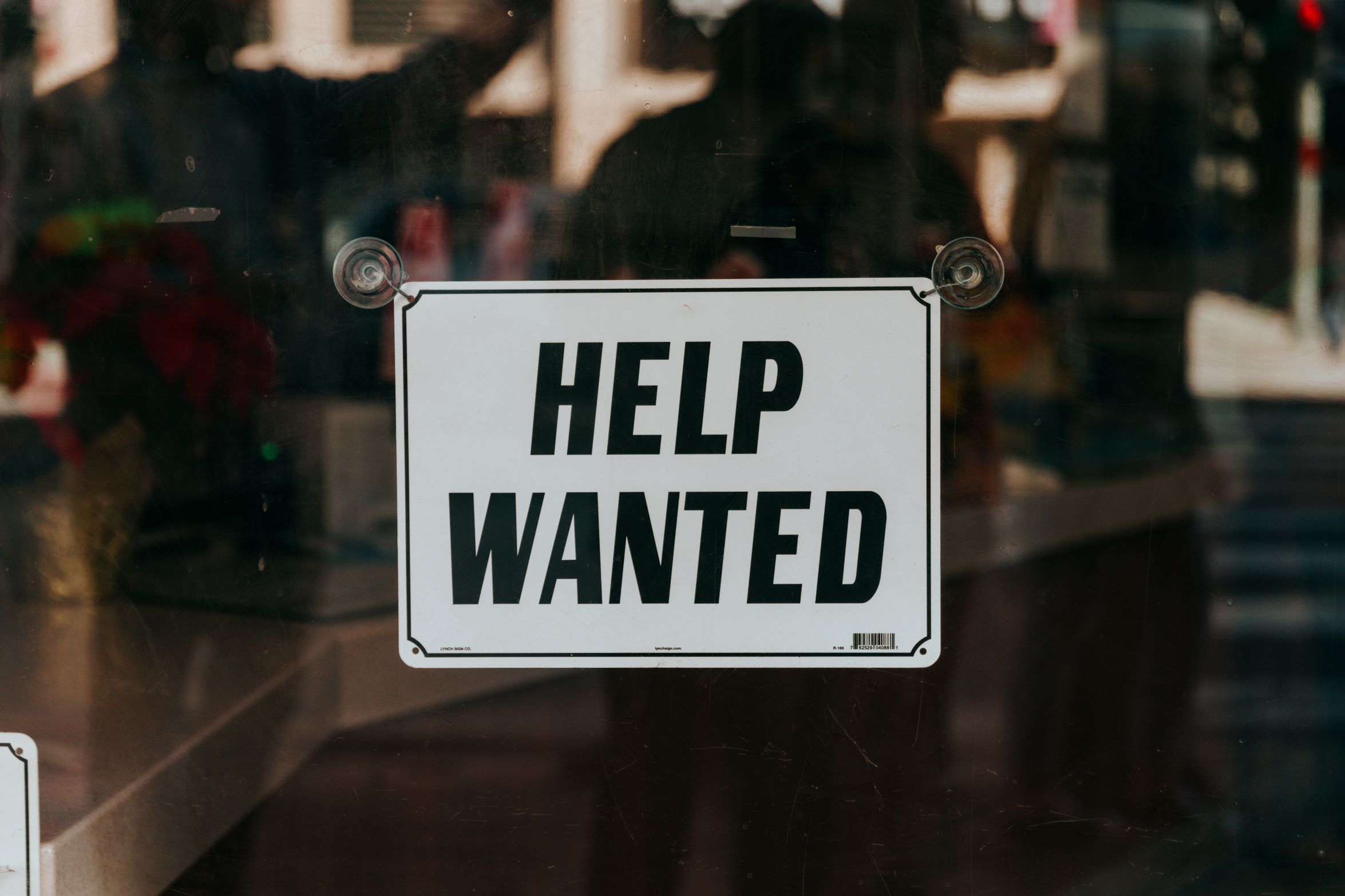 An image of a help wanted sign in a store window.