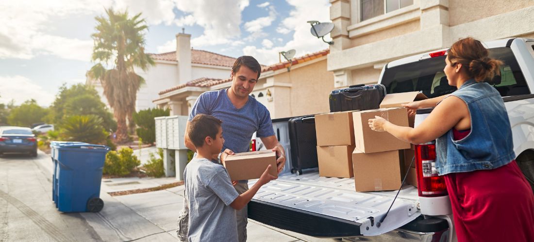 An image of a family packing a truck with moving boxes. 
