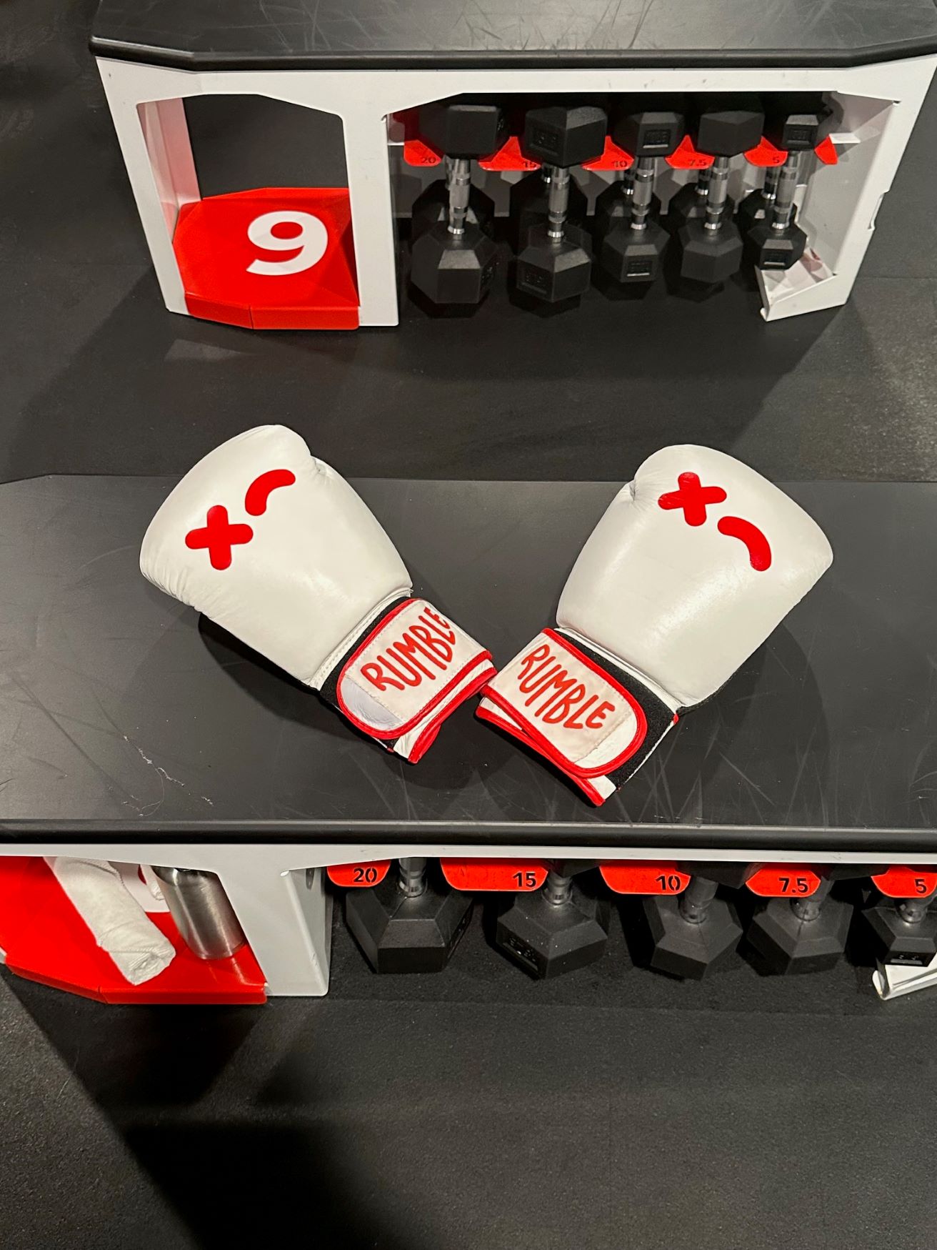 An image of a weight bench with Rumble Boxing gloves on top.