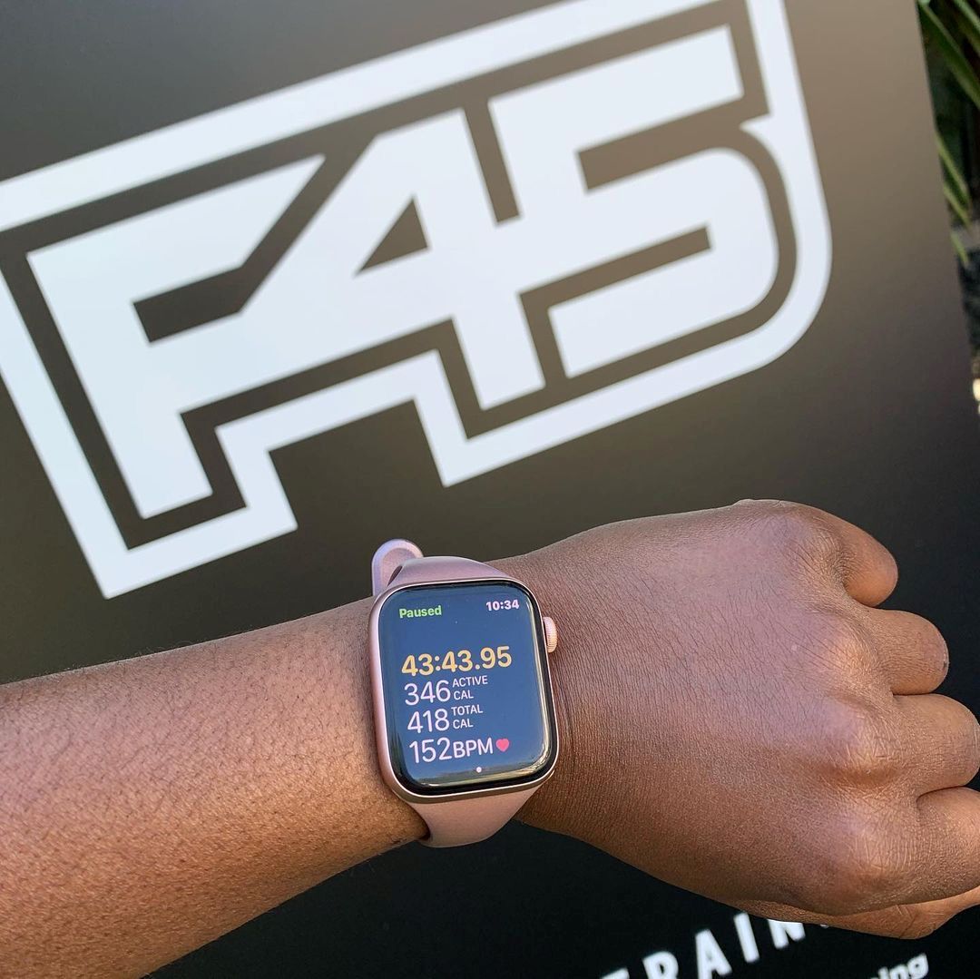 An image of an F45 sign with someone wearing an Apple Watch in front of it