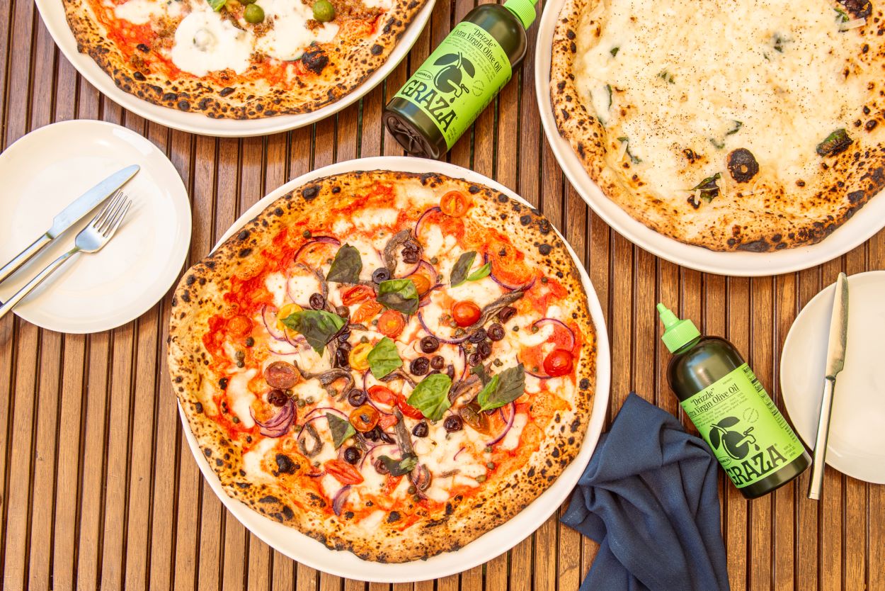 An image of pizzas and Graza olive oil. 
