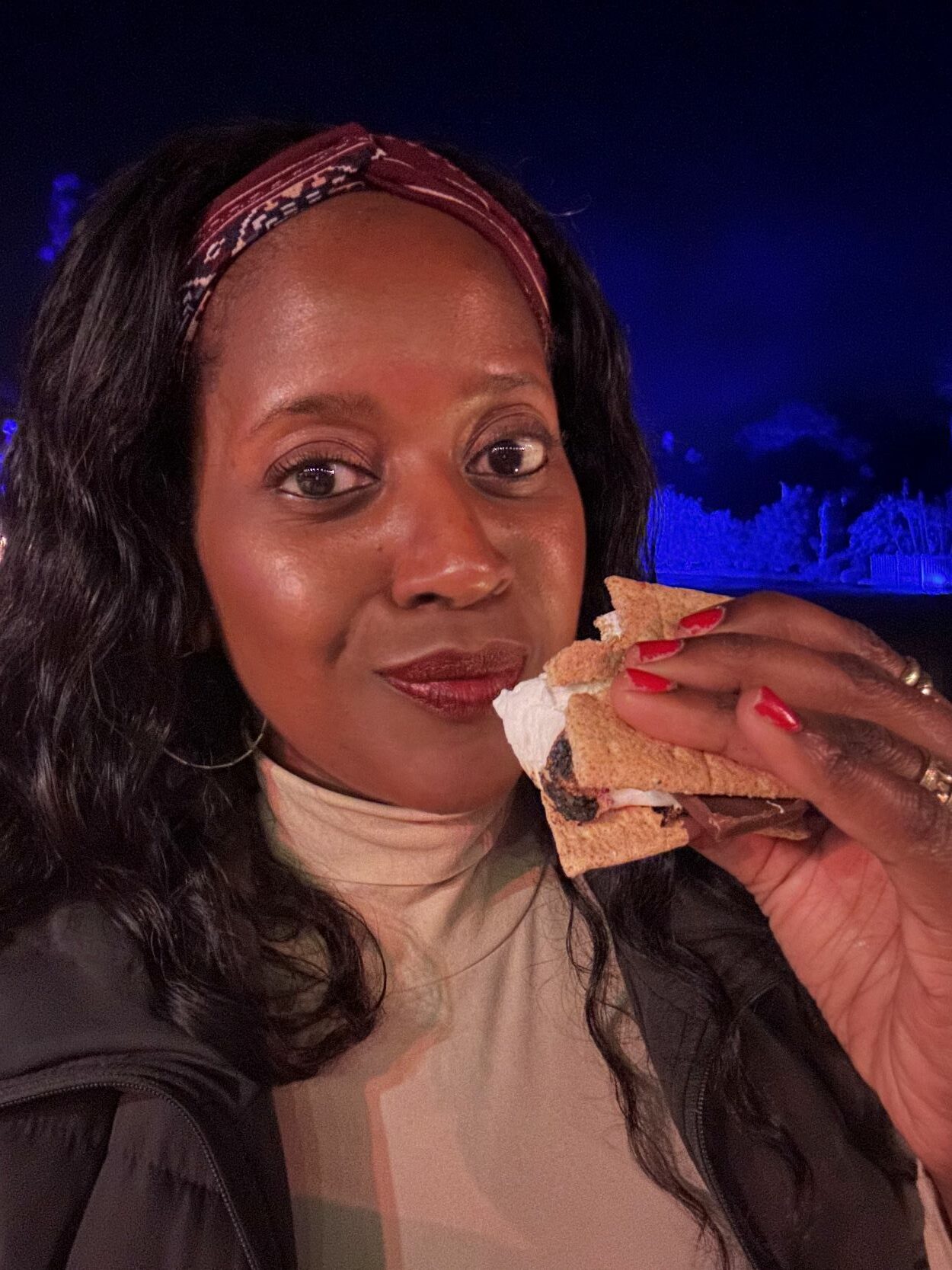 An image of a woman holding a s'more at LIGHTSCAPE Immersive Holiday Light Experience..