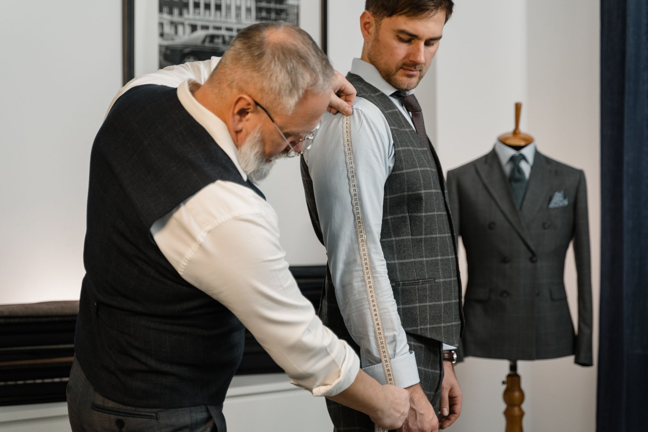 An image of a man having his measurements taken at a tailor.