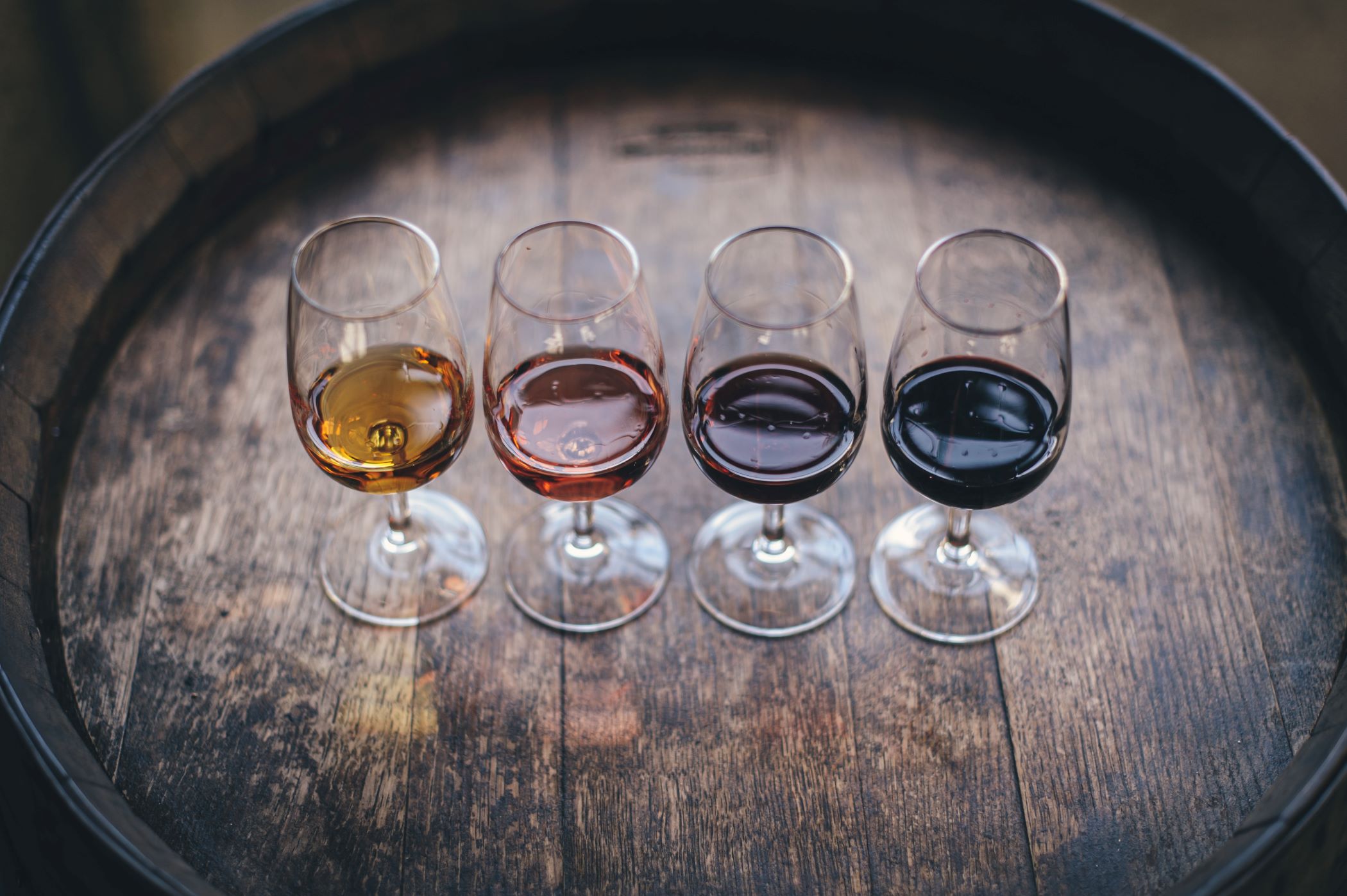 An image of four tasting glasses of wine sitting on top of a barrel.