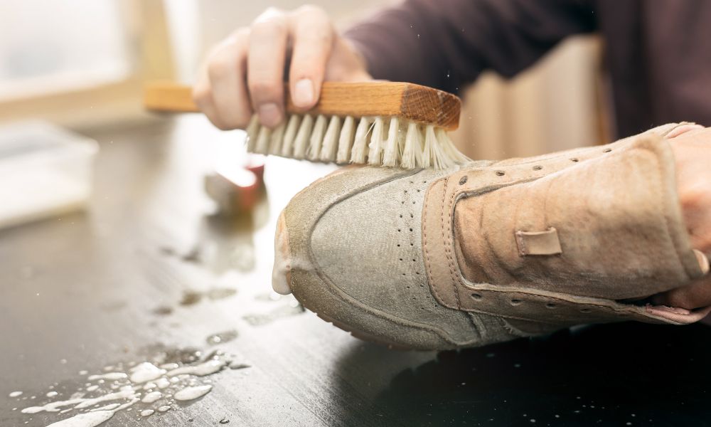 An image of someone scrubbing sneakers clean with a scrub brush.