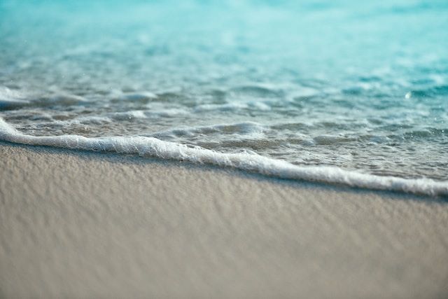 An image of the beach and the ocean waves hitting the sand.
