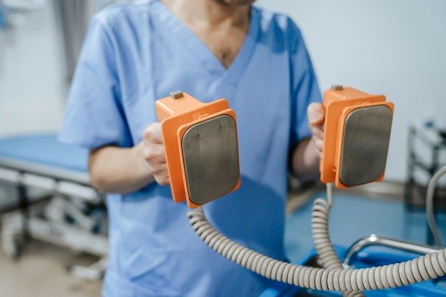 An image of a nurse holding a defibrillator.