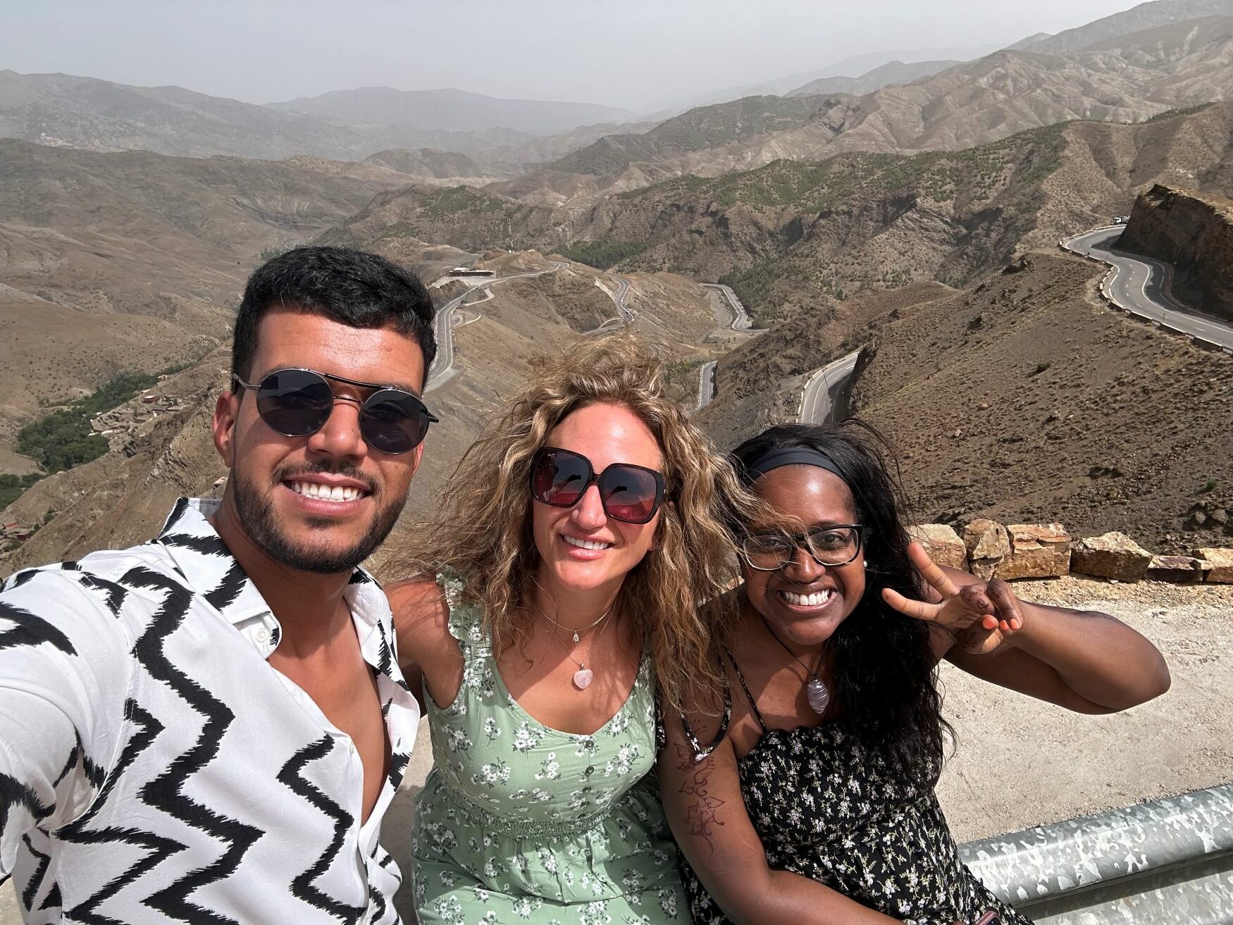 Those seeking luxury escapes bucket list ideas for wanderlust jetsetters need to use luxury travel company Morocco Fabulous Travel. In this image are two women en route to their camel ride with their Morocco Fabulous Tour guide/personal driver. In the background are beautiful mountains.