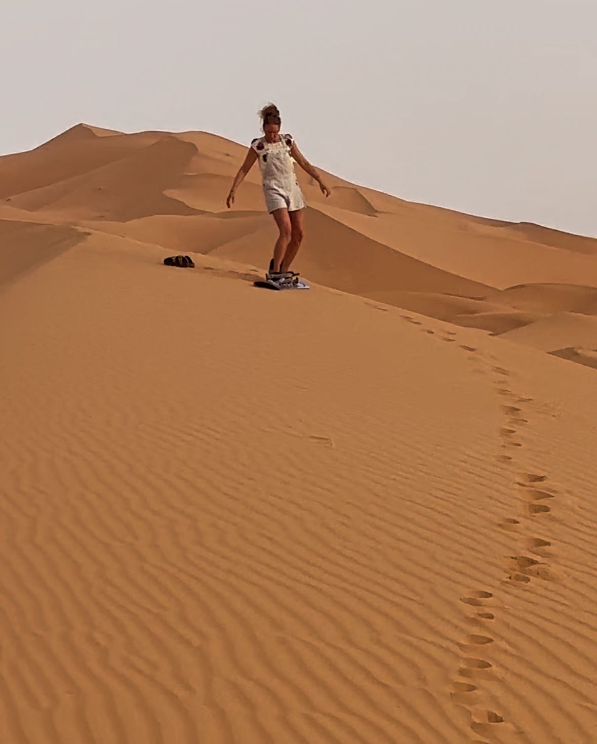 An image of a woman sand surfing in the Moroccan Sahara after her camel ride.