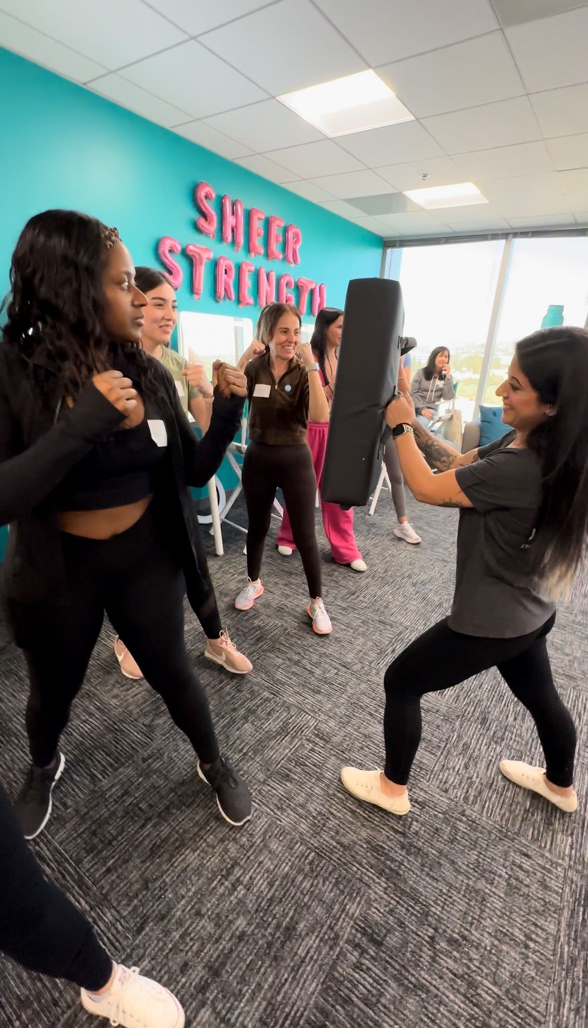 An image of Lifestyle blogger Ariel Johns preparing to practice her self-defense punch during Thrive's Sheer Strength Lip Plumping Peptide Gloss launch event.