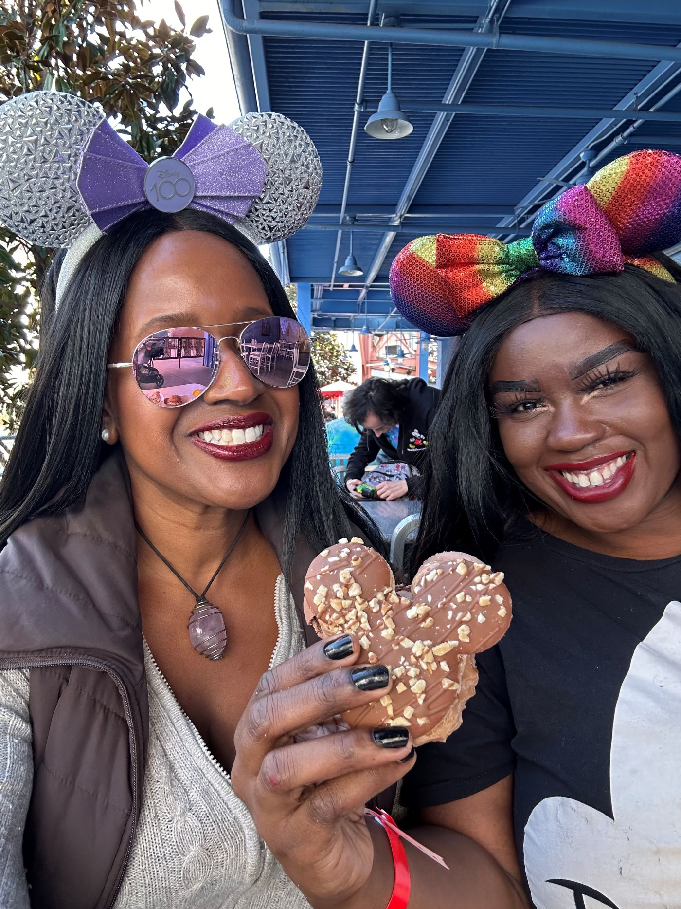 An image of lifestyle blogger Ariel Johns and a friend eating the Mickey-Shaped Macaron at the Disney California Adventure Food & Wine Festival.