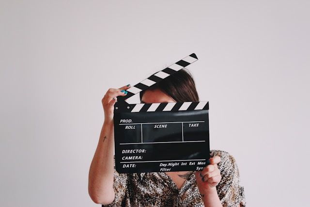 An image of someone holding a clapperboard to represent TV and movies