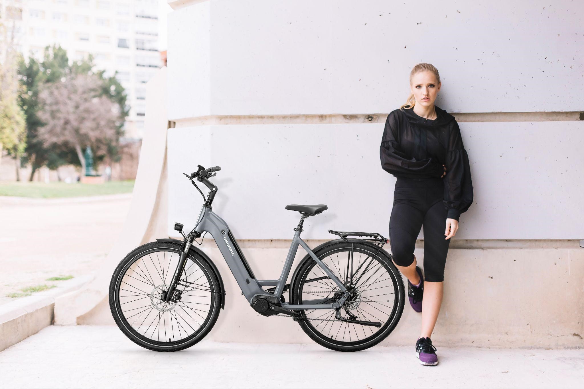 An image of a woman in workout clothes next to her e-bike.