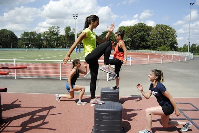 An image of 4 women doing HIIT exercises at  track to craft their summer body.