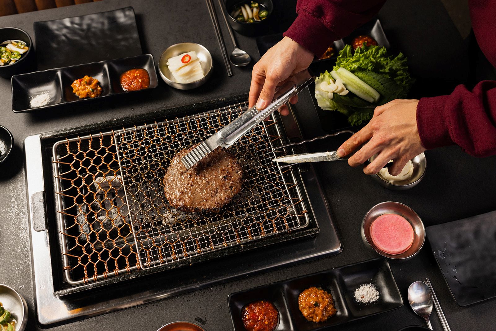 An image of someone cooking the Marinated Short Ribs Patty on a grill. 