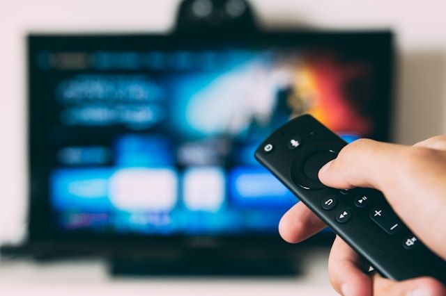 An image of someone pointing a remote at a TV to stream one of the best shows on Hulu.