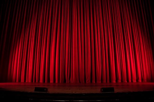 An image of the red curtain down  at a theatre for a show.