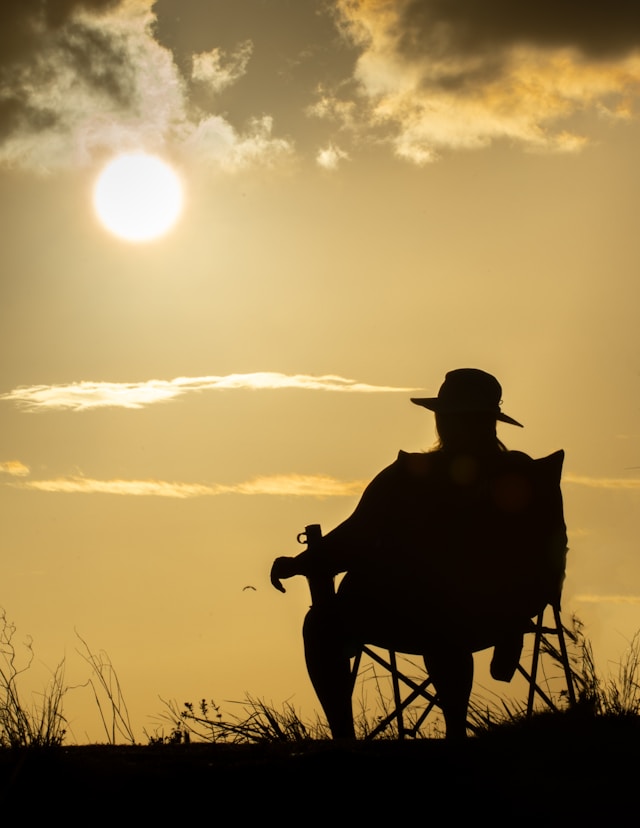 An image of a man sitting alone outside in a chair.