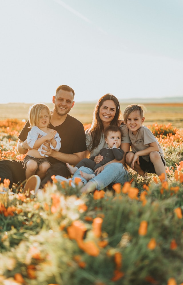 An image of a family sitting in a field of flowers.