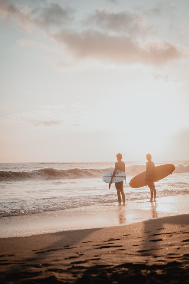 An image of two people with surfboards at the beach.