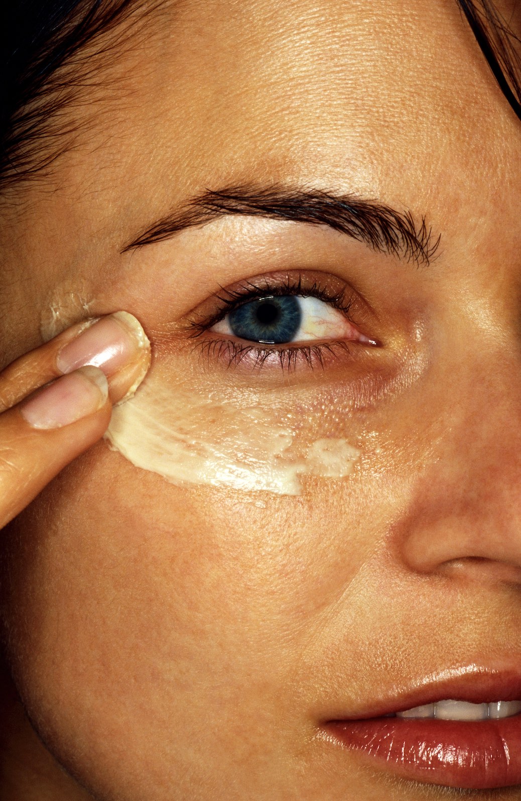 An image of a woman putting on the best eye cream for dark circles.