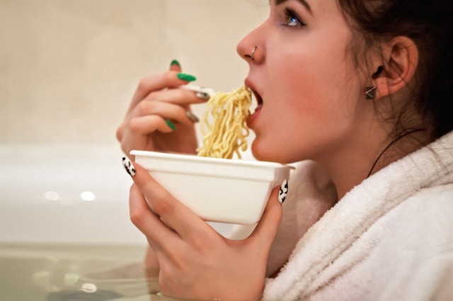 An image of a woman eating ramen noodles. 